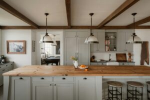 Modern ranch kitchen featuring a large white island, exposed wood beams, and warm pendant lighting