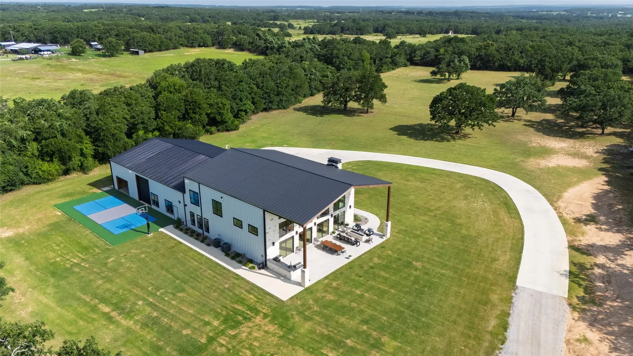 Aerial of the rear elevation with sport court and circular drive