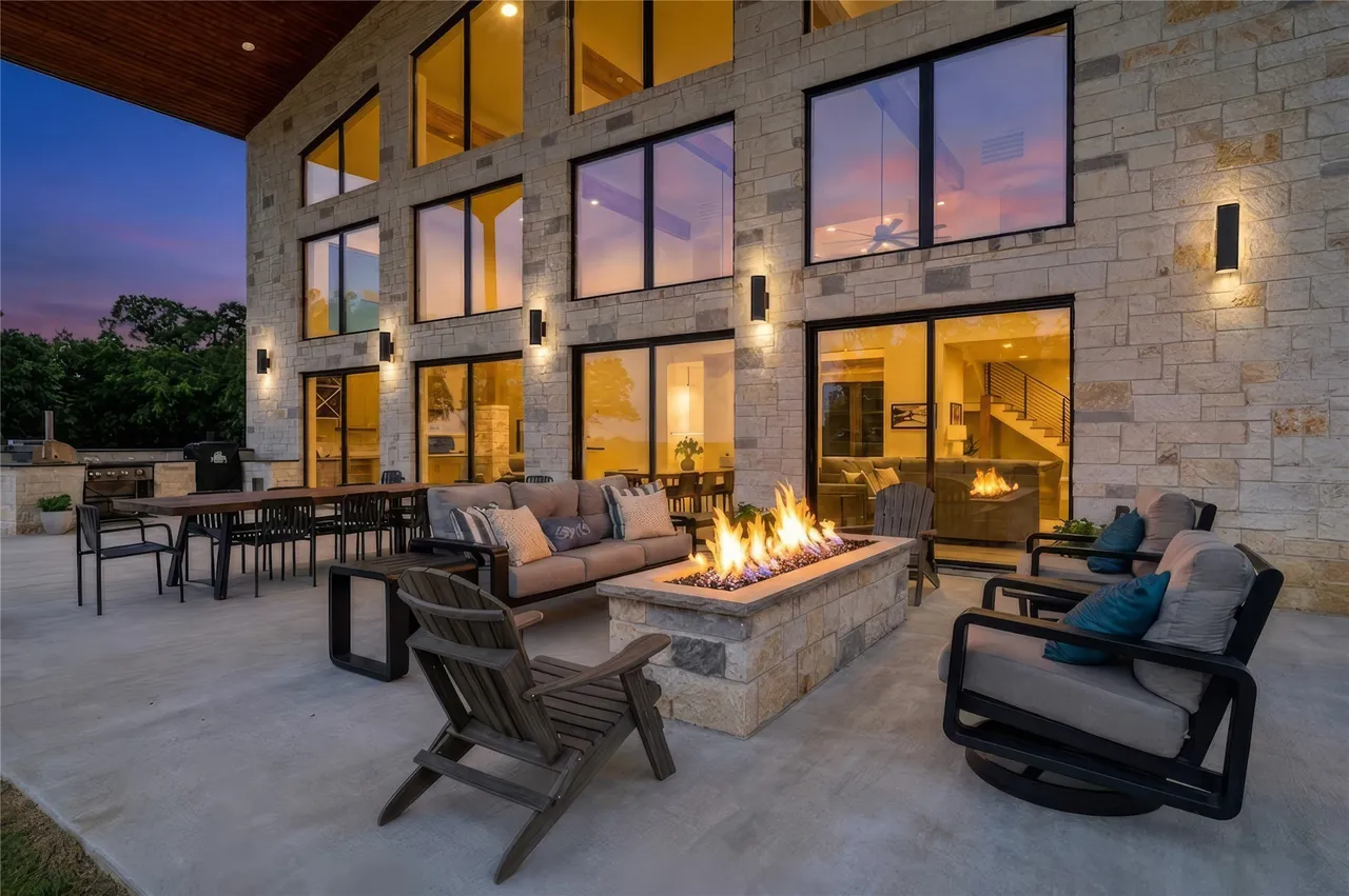 Covered patio at dusk with gas fire table and outdoor kitchen