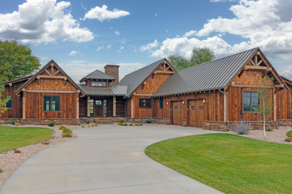 Rustic mountain ranch house plan exterior with wood siding, timber gables, metal roof and curved drive