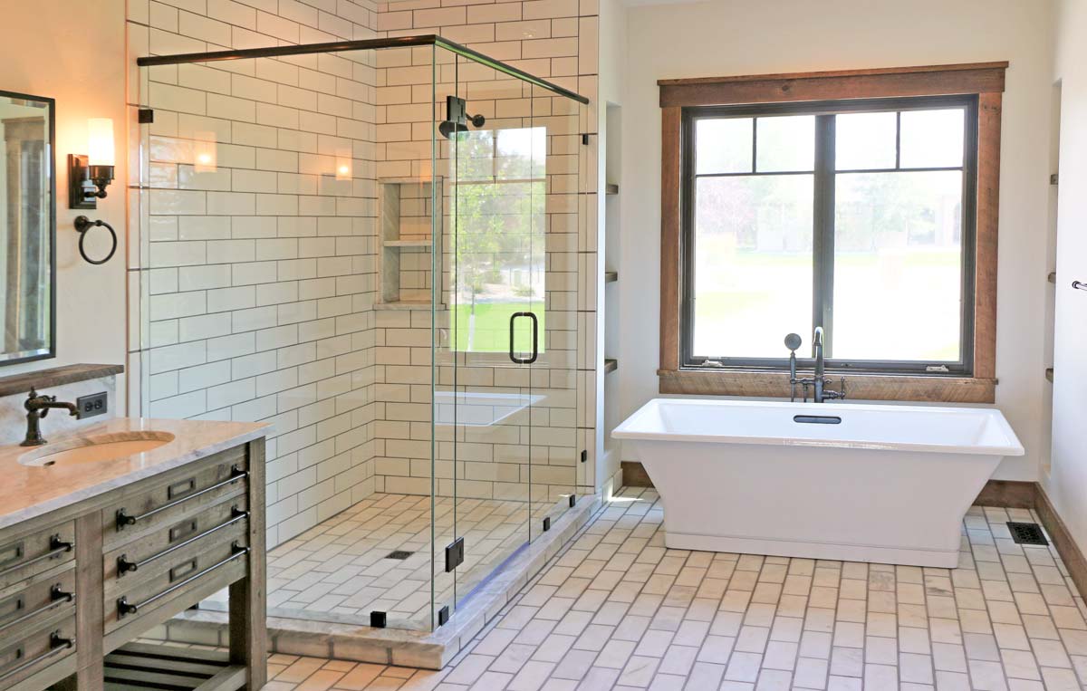 Primary bath with freestanding tub, glass walk-in shower and wood-trimmed window