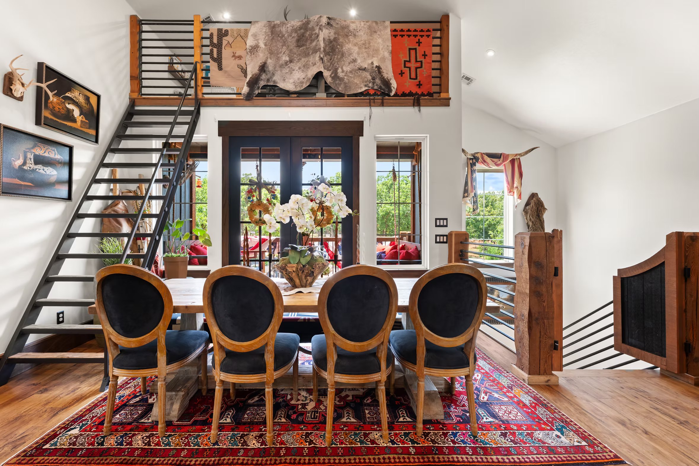 Dining table below the loft edge with a hide draped over the railing