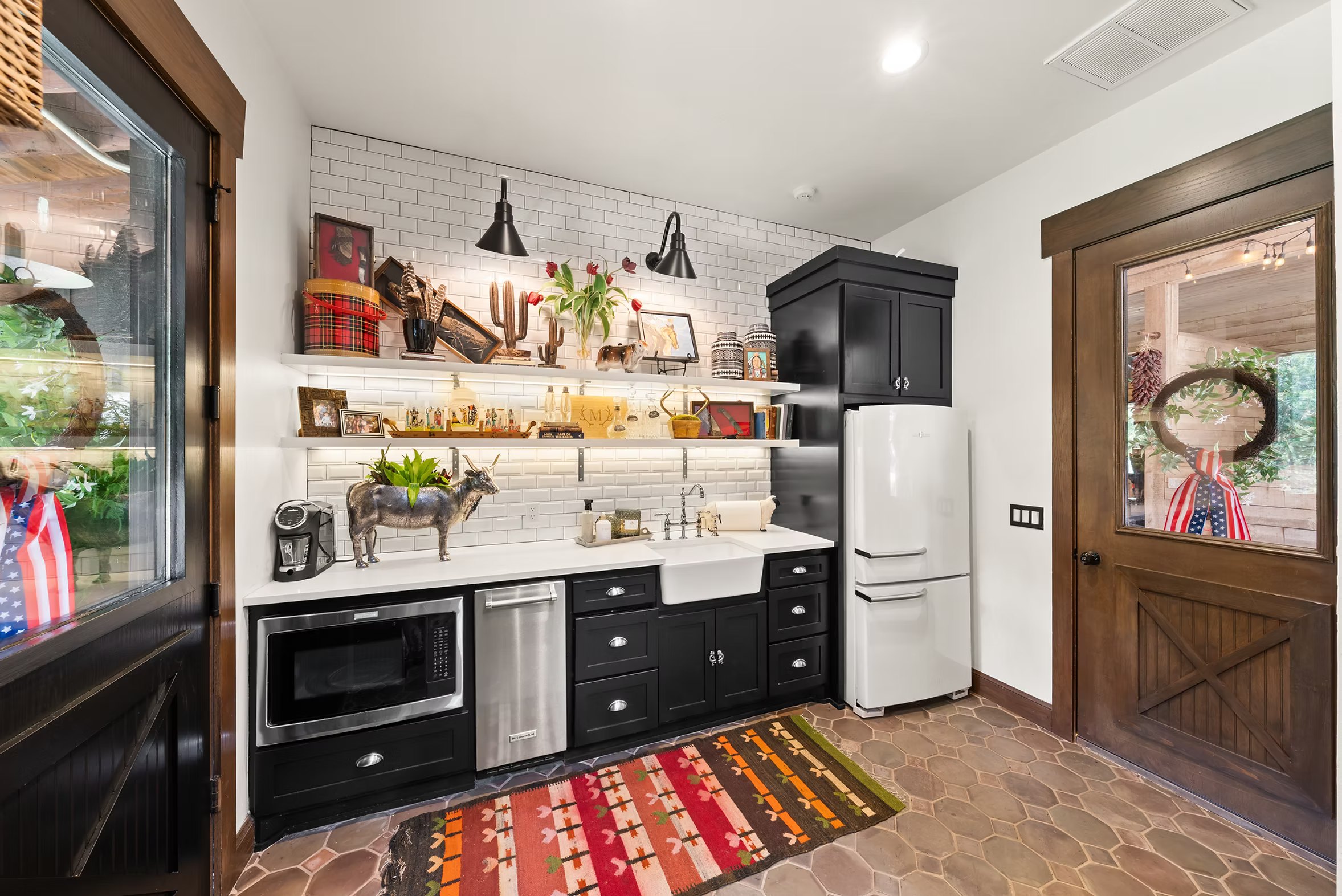 Barn level kitchenette with black cabinetry, white subway tile and open wood shelves