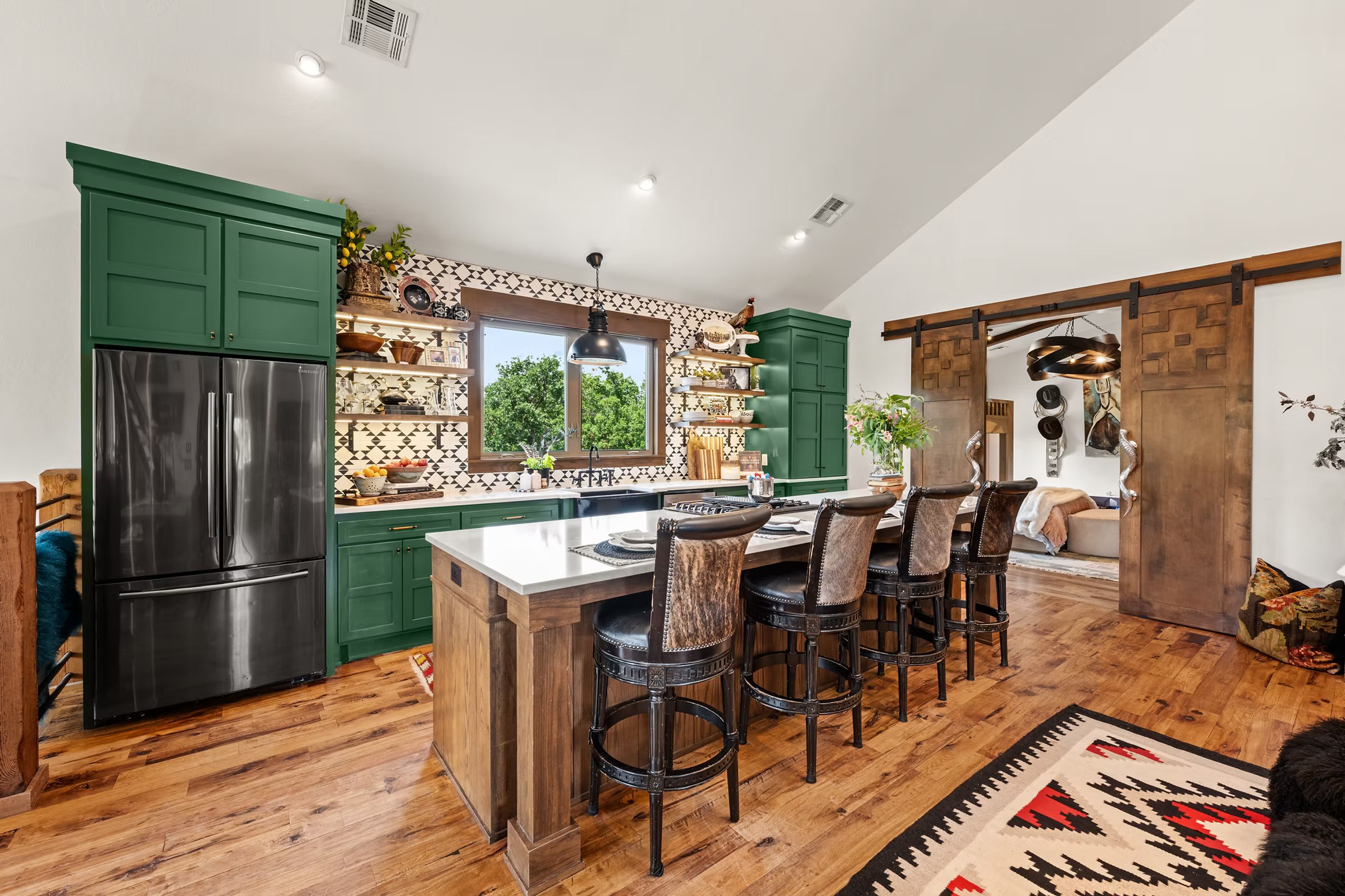 Kitchen island with dark upholstered stools opening to the dining area