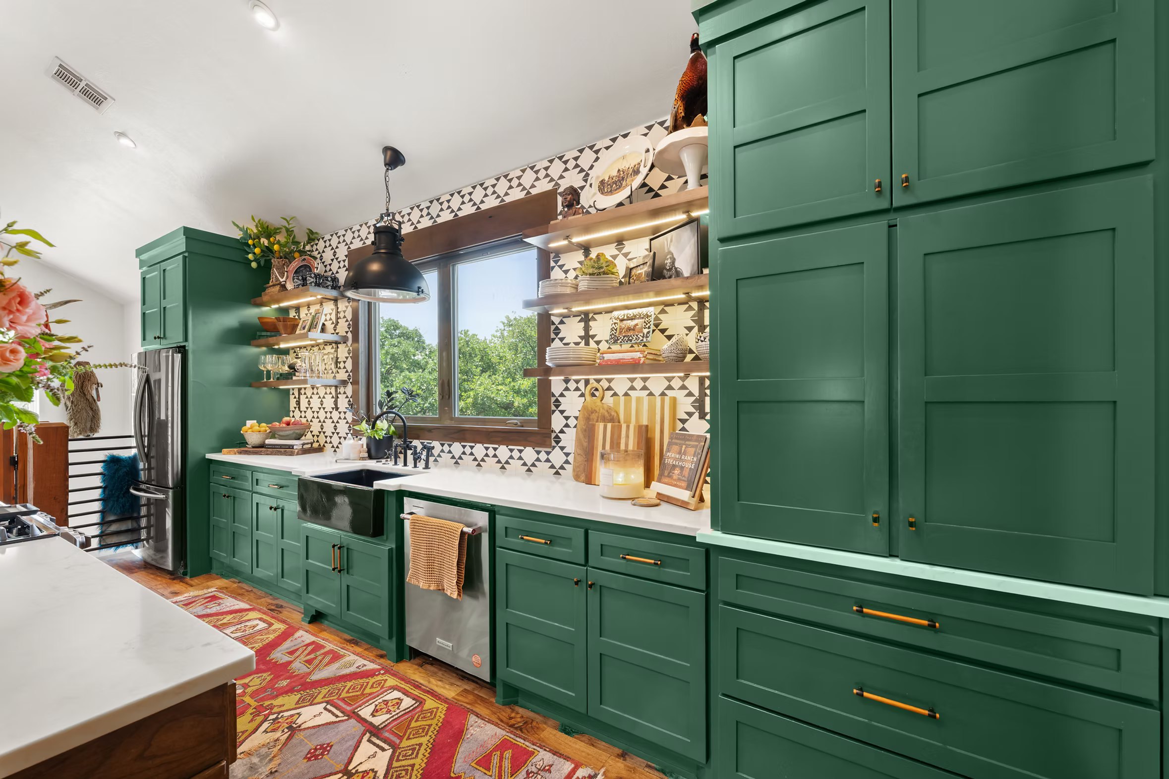 Kitchen with saturated green floor to ceiling cabinetry and black and white geometric tile