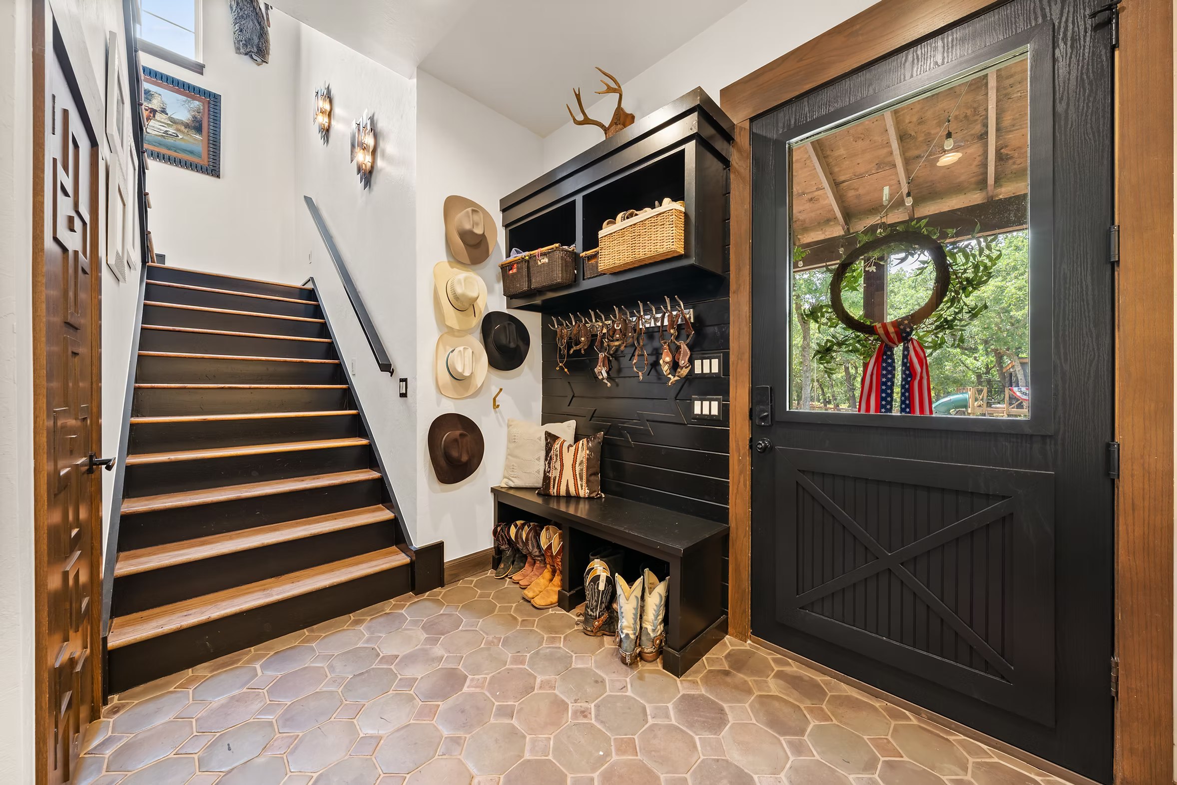 Landing and staircase with Saltillo tile, art and tack against black paneling
