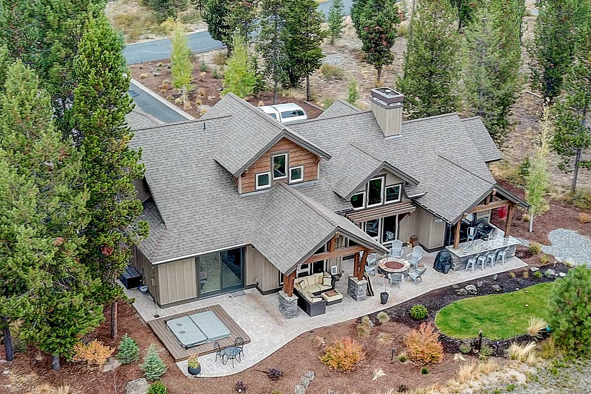 Aerial view of mountain home with covered patio, outdoor kitchen and hot tub deck