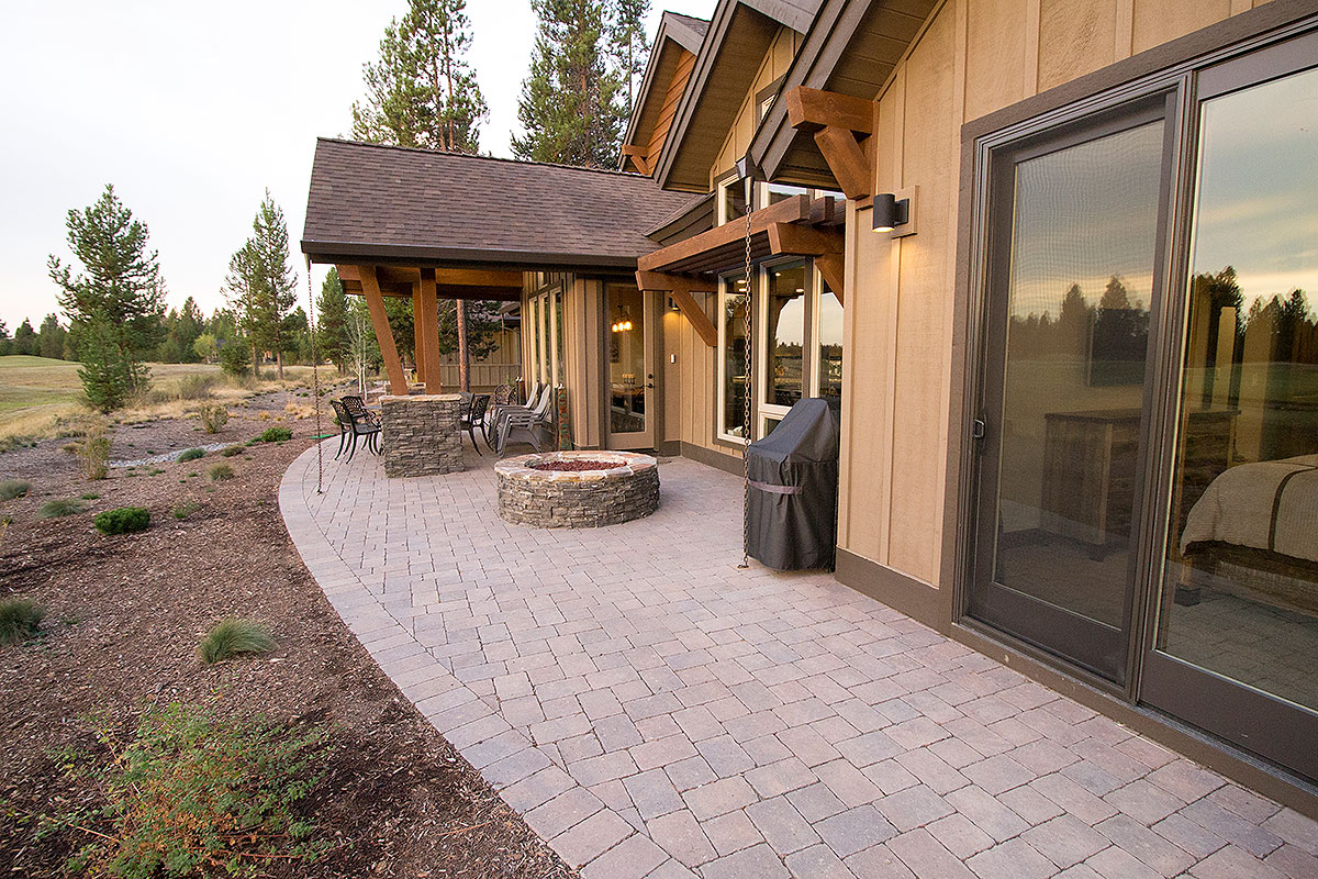 Mountain home rear covered patio with stone fire pit and large windows