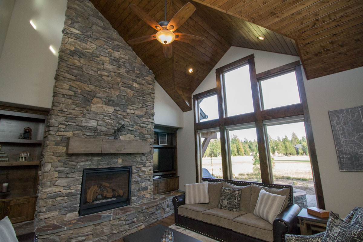 Vaulted great room with floor-to-ceiling stone fireplace, wood plank ceiling and large windows