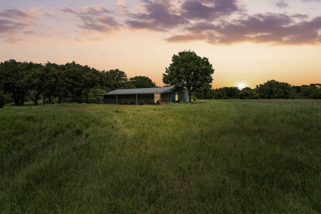 Sunset over the open pasture and pole barn on 78 acres off Coalville Road in Gordon, Texas