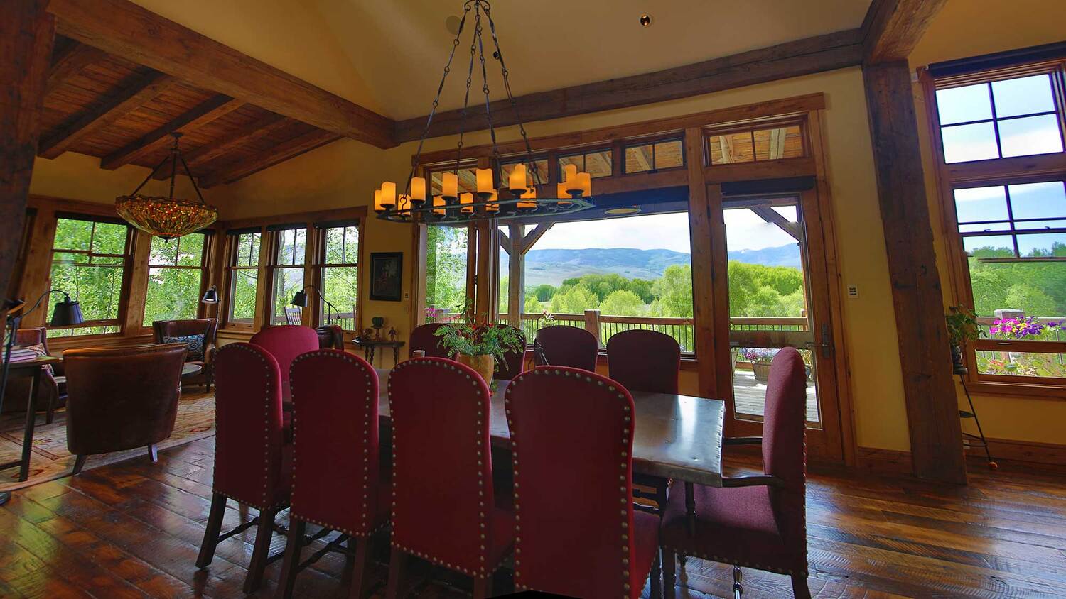 Long dining table beneath timber beams with windows to the view at Eagle Ridge Ranch