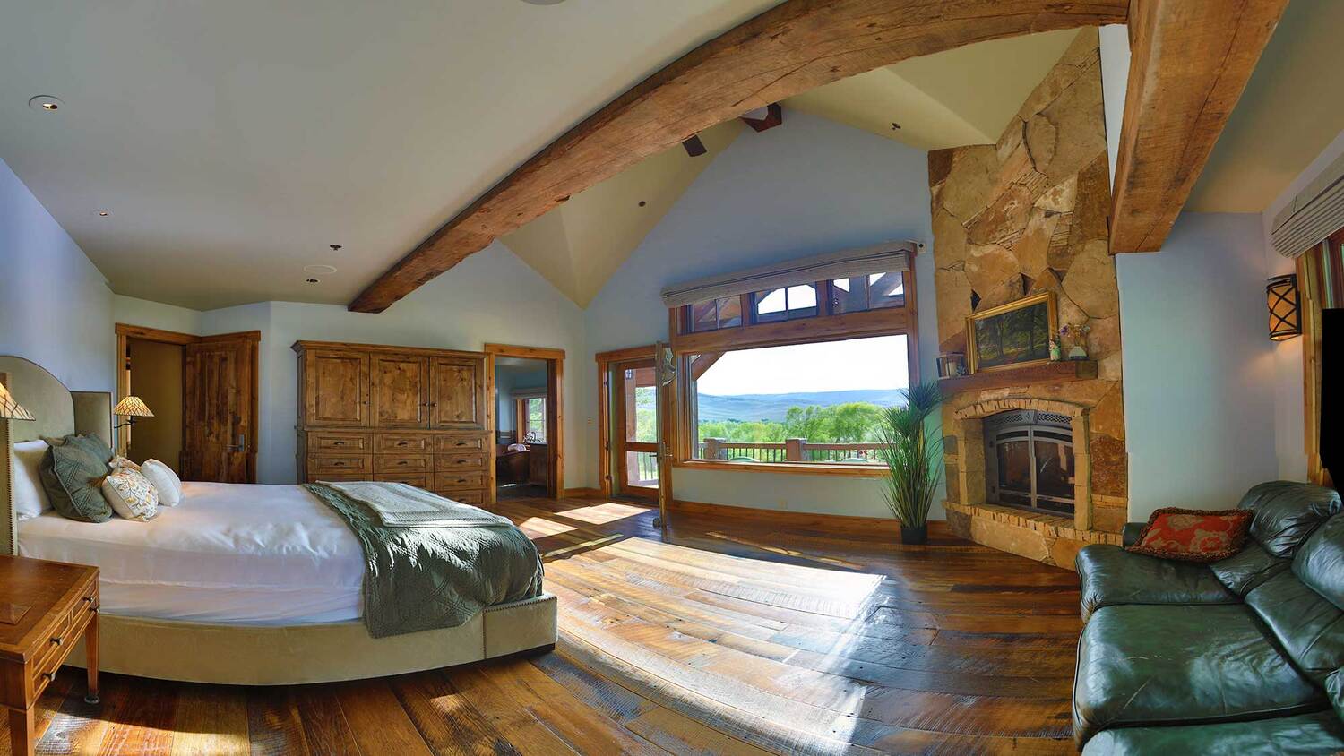 Primary bedroom with a stone fireplace and mountain views at Eagle Ridge Ranch