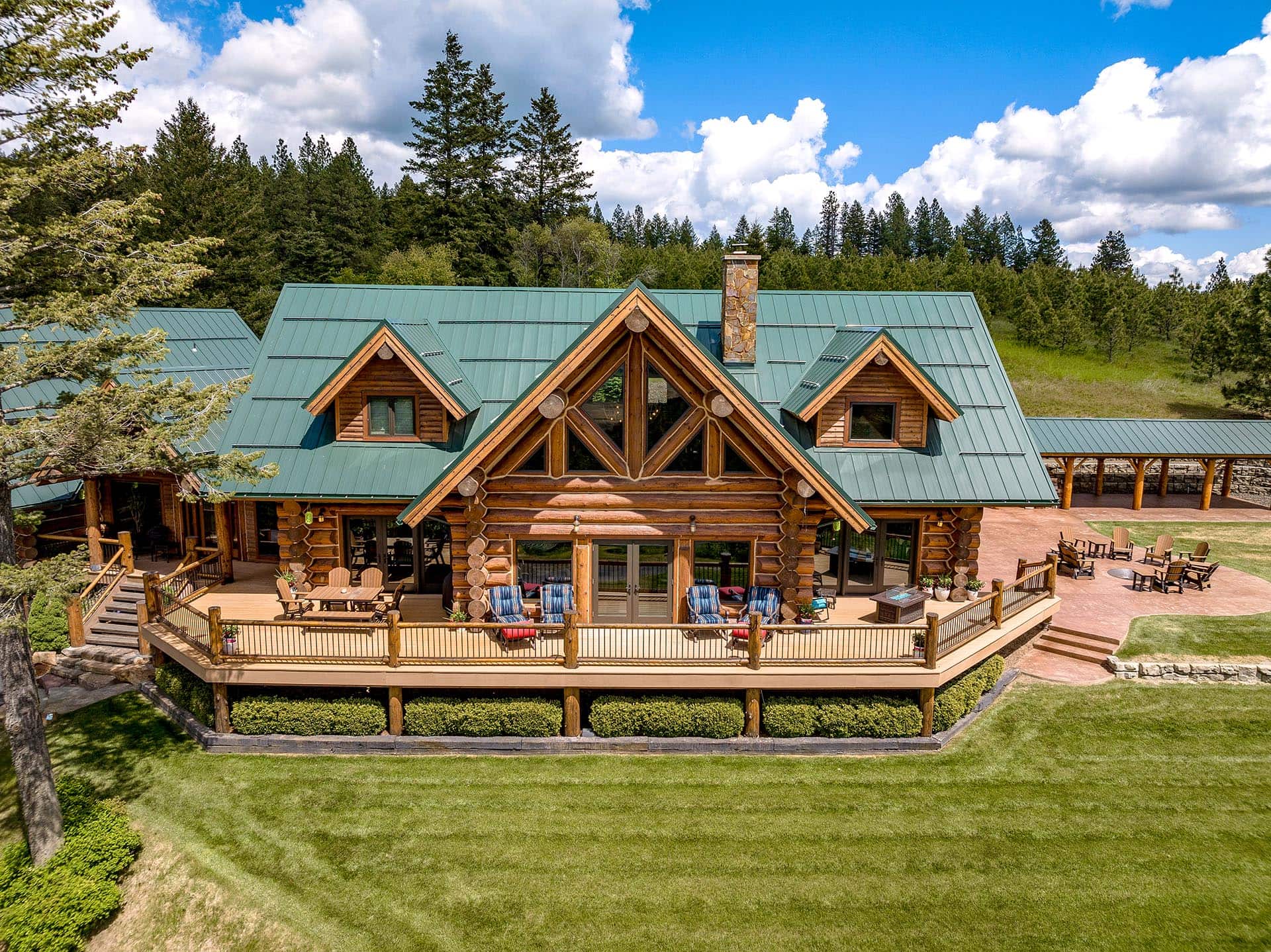 Green-roofed custom log home at Painted Rose Ranch in Worley, Idaho